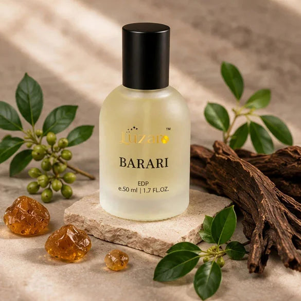 Luzaro Barari EDP 50ml frosted perfume bottle with black cap on beige stone slab surrounded by oud wood chips, amber resin and green berries with soft sunlight – luxury woody amber fragrance lifestyle shot