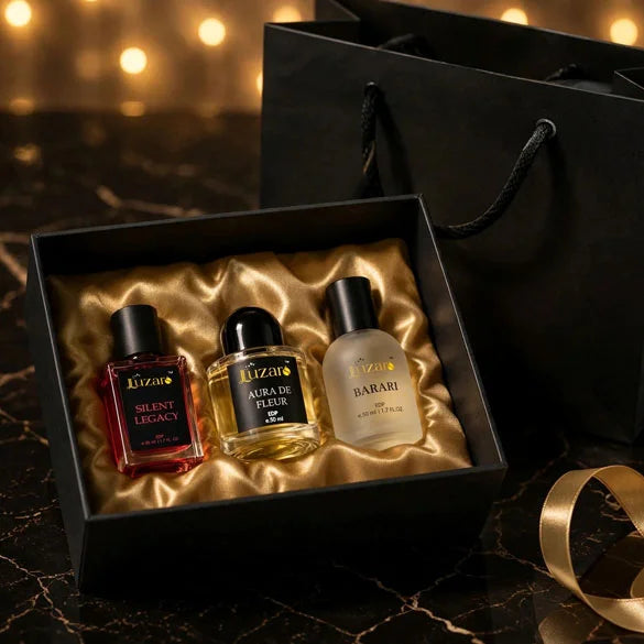 Luzaro perfume gift set trio - Silent Legacy, Aura De Fleur and Barari EDP 50ml bottles in black box with gold satin lining on black marble with gold ribbon and shopping bag – luxury fragrance gift collection lifestyle shot